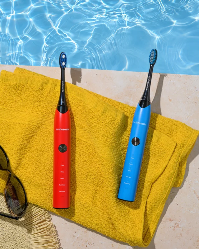 Red and blue Smilesonic toothbrushes by a pool
